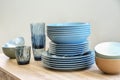 Stack of ceramic plates, bowls and glasses on wooden table Royalty Free Stock Photo