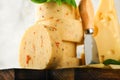 Stack of cheese with tomatoes and seasoning and Swiss cheese on with basil and knife on serving board on light grey table backgrou Royalty Free Stock Photo