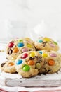 Stack of children cookies with colorful chocolate candies in a sugar glaze on a white light wooden background. Selective focus