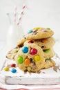 Stack of children cookies with colorful chocolate candies in a sugar glaze on a white light wooden background. Selective focus