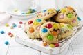 Stack of children`s cookies with colorful chocolate candies in a sugar glaze on a white light wooden background. Selective focus Royalty Free Stock Photo
