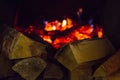 Stack of chipped firewood lit warm lamp light, fuel for the fireplace fire dried on a blurred background of bright burning red coa Royalty Free Stock Photo