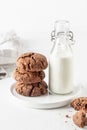 Stack of chocolate brownie cookies with bottle of milk on white background. Homemade crinkle cookies