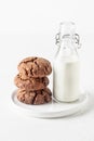 Stack of chocolate brownie cookies with bottle of milk on white background isolated. Homemade crinkle cookies