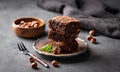 A stack of chocolate brownies with mint and hazelnuts on a dark background with nuts