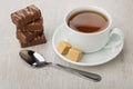 Stack of chocolate candies, cup of tea, sugar and teaspoon Royalty Free Stock Photo