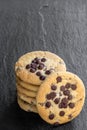 Stack of chocolate chip cookies on black stone background