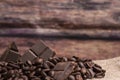 Stack of chocolate chunks with coffee beans on a wooden background, horizontal with copy space