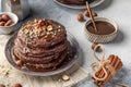 Stack of chocolate pancakes topped with nuts and drizzled with chocolate syrup served on a plate for breakfast, gray background Royalty Free Stock Photo
