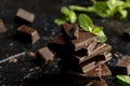 Stack of chocolate pieces with a leaf of mint on dark background Royalty Free Stock Photo