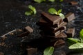 Stack of chocolate pieces with a leaf of mint on dark background Royalty Free Stock Photo