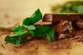 Stack of chocolate pieces with a leaf of mint on wooden background Royalty Free Stock Photo