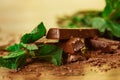 Stack of chocolate pieces with a leaf of mint on wooden background Royalty Free Stock Photo