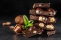 Stack of chocolate slices with mint leaf.Hazelnut and almond milk and dark chocolate pieces tower.Sweet food photo concept. The Royalty Free Stock Photo