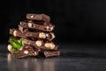 Stack of chocolate slices with mint leaf.Hazelnut and almond milk and dark chocolate pieces tower.Sweet food photo concept. The Royalty Free Stock Photo