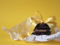 Stack of chocolate slices with a ribbon on the yellow background. Concept of antioxidants, desire, sweet gift