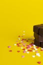 A stack of chocolates on a background of confetti from small hearts. yellow background Royalty Free Stock Photo