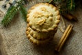 Stack of Christmas mince pies on burlap cloth with fir tree branches and cinnamon sticks, top view,close up Royalty Free Stock Photo