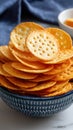 Stack of circular crackers in a blue ceramic bowl on a marble surface with a blue cloth and cheese in the background. Royalty Free Stock Photo