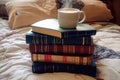 A stack of classic books rests on a bed, with a steaming cup of coffee placed on top. Royalty Free Stock Photo