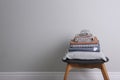 Stack of clean bed linen and pillow on stool near light grey wall. Space for text Royalty Free Stock Photo