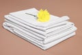 Stack of clean bed linens and beautiful flower on beige background, closeup Royalty Free Stock Photo