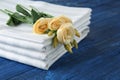 Stack of clean bed sheets and flowers on color wooden background Royalty Free Stock Photo