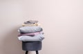 Stack of clean bed sheets and pillows on stool near beige wall. Space for text Royalty Free Stock Photo