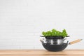 Stack of clean cookware with lettuce on table against brick wall. Space for text Royalty Free Stock Photo