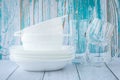 A stack of clean dishes on a turquoise wood wall background. Ceramic white plates and transparent glasses Royalty Free Stock Photo