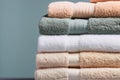 Stack of clean folded white beige terry towels on gray wall background. Laundry spa wellness cleanliness concept. Scandinavian