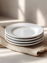 Stack of clean white ceramic plates on beige tablecloth in bright kitchen Royalty Free Stock Photo