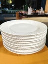 A stack of clean white plates with a patterned rim on an orange tablecloth Royalty Free Stock Photo