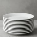 Stack of clean white porcelain plates on a gray tabletop. The plates are aligned neatly, Royalty Free Stock Photo