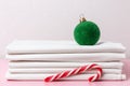 A stack of clean white sheets, a Christmas tree ball, and a candy cane