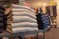 A stack of clothes in the store, pullovers and sweatshirts nicely and neatly stacked in bundles on the table, beige and