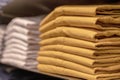 A stack of clothes in the store, pullovers and sweatshirts nicely and neatly stacked in bundles on the table, yellow