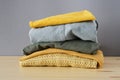 Stack of clothes on wooden table and grey background isolation