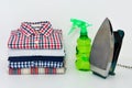 Stack of plaid shirts with iron and foggy spray on white background Royalty Free Stock Photo