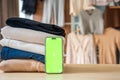 Stack of clothing prepared for resale with a smartphone displaying green screen for mockup use. Mobile apps simplify Royalty Free Stock Photo