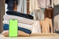 Stack of clothing prepared for resale with a smartphone displaying green screen for mockup use. Mobile apps simplify Royalty Free Stock Photo