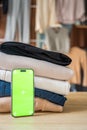 Stack of clothing prepared for resale with a smartphone displaying green screen for mockup use. Mobile apps simplify Royalty Free Stock Photo