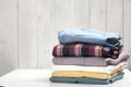 Stack of clothing on white table wooden plank background.Folded clothes pile empty copy space