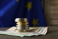 Stack of coins and banknotes on wooden table against European Union flag, space for text Royalty Free Stock Photo