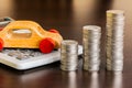 Stack of coins with calculator and wooden car on wood table Royalty Free Stock Photo