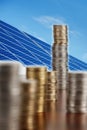 Stack of coins in front of photovoltaics composing Royalty Free Stock Photo