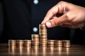 a stack of coins getting progressively taller, hand placing the top coin