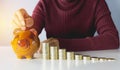 Stack coins with hand of female drop the coin into piggy bank. Royalty Free Stock Photo