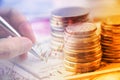 Stack of coins and a hand holding a ballpoint pen is examining a technical chart of financial instrument. Royalty Free Stock Photo