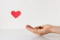 Stack of coins on hand and red heart symbol on the white background. Donation, charity, finance or investment concept. Royalty Free Stock Photo